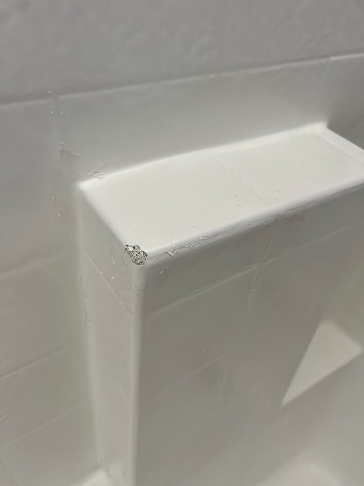 Chipped corner of plastic bathtub shelf